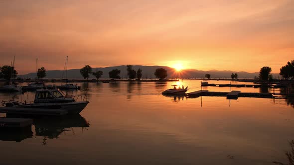 Panning view of boat pulling up to dock during colorful sunset on Utah Lake