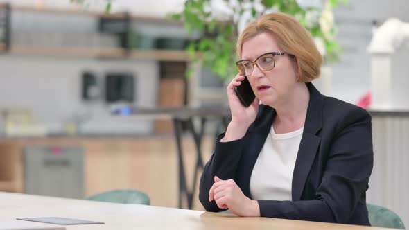 Angry Businesswoman Talking on Smartphone in Office