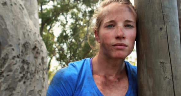 Portrait of fit woman leaning on wooden pole during obstacle course