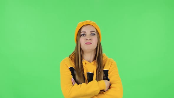 Portrait of Modern Girl in Yellow Hat Is Standing Offended and Then Smiling. Green Screen