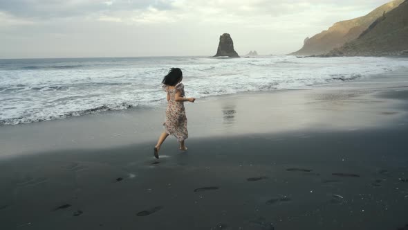 Young Woman in a Beautiful Dress Runs Along the Black Volcanic Black Sand Beach Benijo in the North