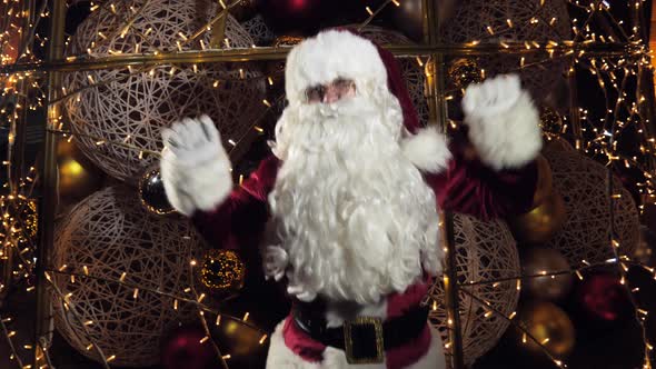 Jolly Santa Claus Waving Two Hands and Dancing or Recording a Virtual Greeting on Christmas Eve