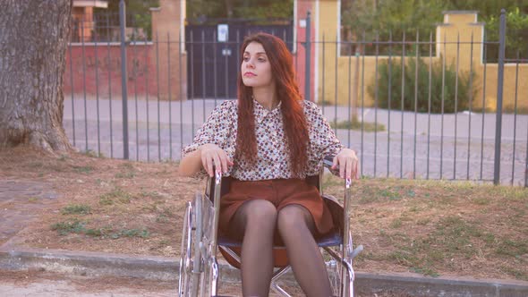 living with disability - young woman using wheelchair alone at park looks around
