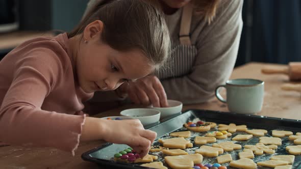 Caucasian girl decorating homemade cookies with grandmother. Shot with RED helium camera in 8K
