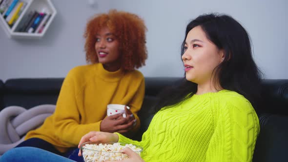 Multiracial Friendship. Afican American Black and Asian Woman Eating Popcorns Gossiping and Watching