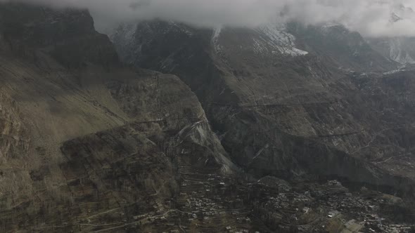 Aerial Dolly Flying Over Hunza Valley With View Of Mountain Ravine Tilt Down To Village Town On Vall