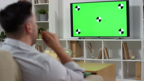 Man Eating Chips and Watching News on TV