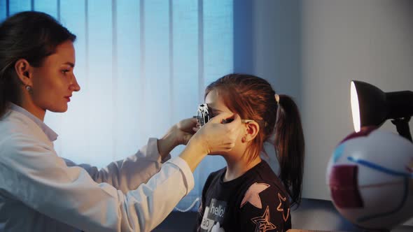 The Ophthalmologist Examines the Patient Teen Girl Eye and Puts on a Device for Selecting Lenses for