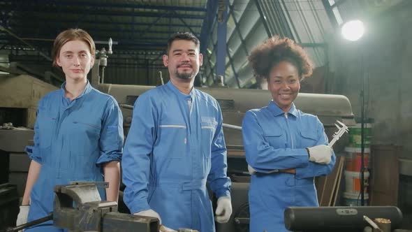 Multiracial workers collaborate and express happy work in a mechanical factory.