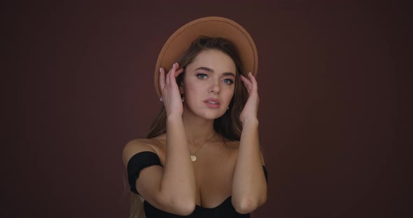 Attractive Girl in a Brown Hat Smiling Straightening Her Hair