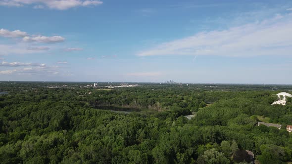 Drone view over outside Minneapolis with extensive green foliage and small lake. Blue sky. alt