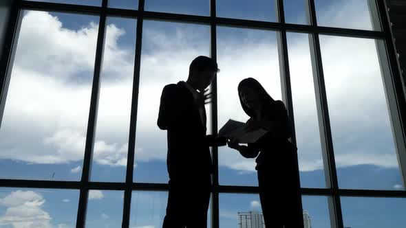 Silhouettes of two business people discussing in the office.