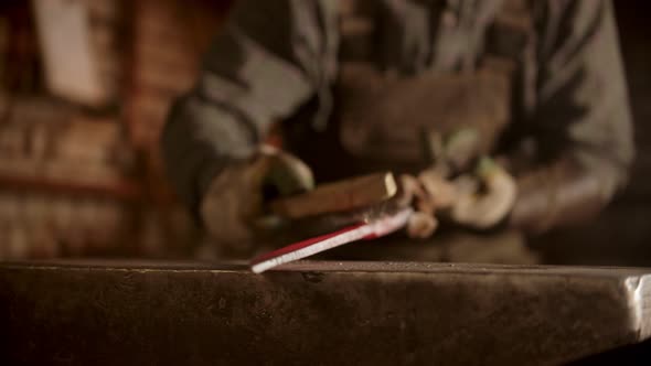 A Man Blacksmith Forging a Knife in Gloomy Workshop