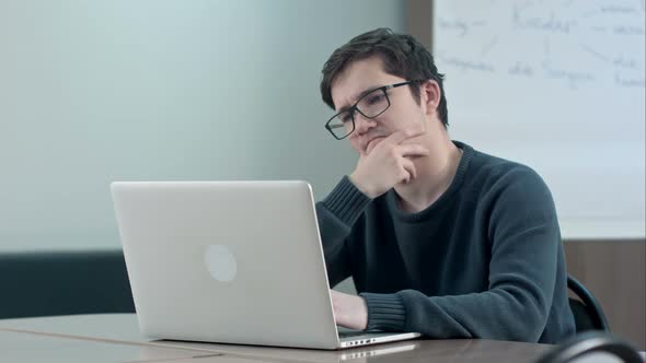 Pensive Student with Laptop Studying in the University Library