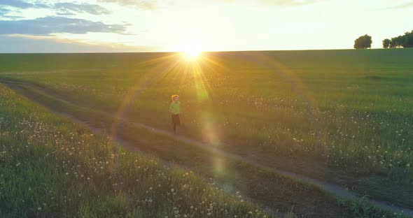 Sporty Child Runs Through a Green Wheat Field. Evening Sport Training Exercises at Rural Meadow. A