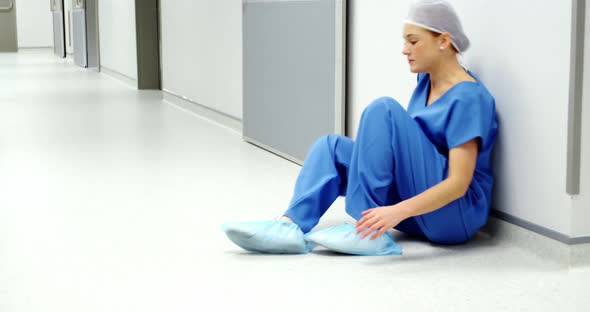 Worried nurse sitting on the floor