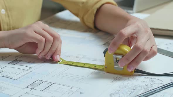 Close Up Of Hand's Woman Engineer Measuring Blueprint At The Office
