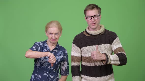 Happy Grandson Giving Thumbs Up While Upset Grandmother Giving Thumbs Down