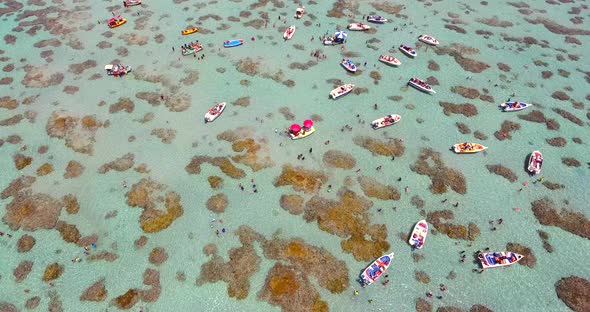 Aerial view of boats and people swimming in turquoise sea of Rio do Fogo, Brazil