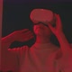 Young woman looking around wearing virtual reality goggles in red light - VideoHive Item for Sale