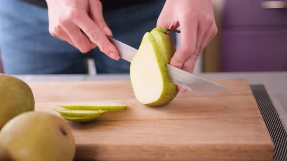 Cutting Slicing Fresh Pear with Knife on a Domestic Kitchen