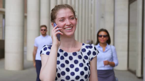 Medium Shot of Businesswoman Talking Over Cellphone and Walking in Urban City Street