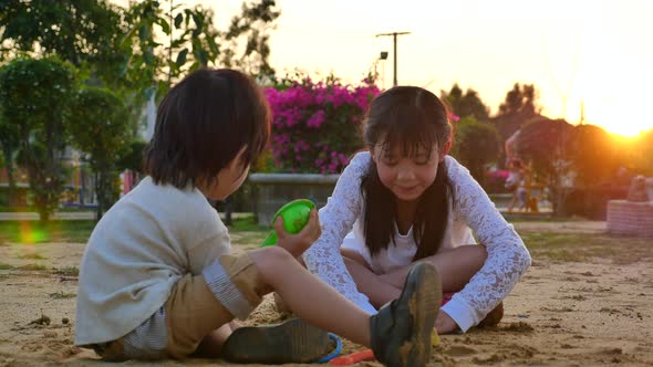 Asian Children Playing Sand In Playground Under Sunset