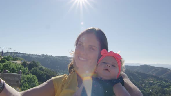 Mother Taking Selfie with Baby Daughter in Front of Beautiful Mountain View