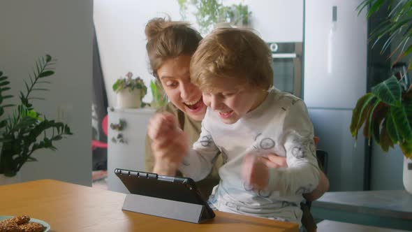 Excited Mother and Kid Playing on Digital Tablet at Home