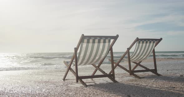 Two empty deckchairs standing on beach at sunset