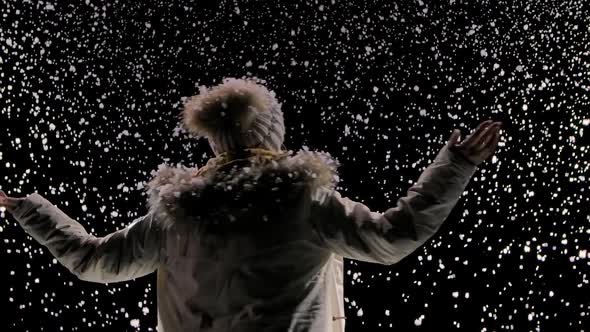 Bottom View of a Happy Young Woman in a Hat and Warm Clothes Whirling Among the Falling Snow. Large