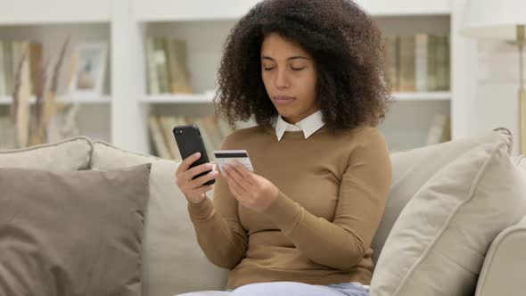 Online Payment Loss on Smartphone By Young African Woman on Sofa
