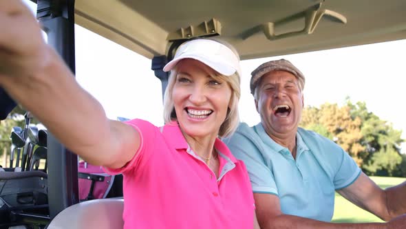 Two golfers driving in their golf buggy