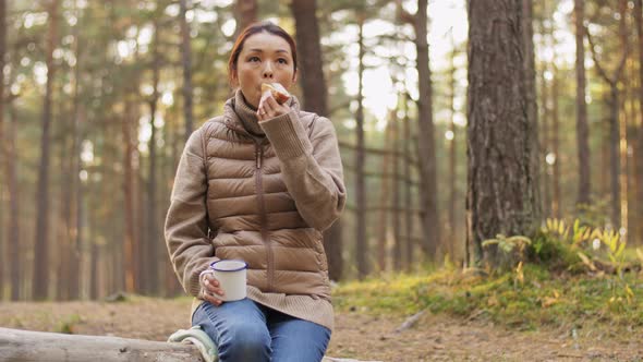 Woman with Mushrooms Drinks Tea and Eats in Forest