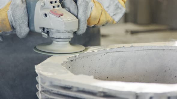 Clouse up of a worker's hands polishing a metal casting part using a grinder