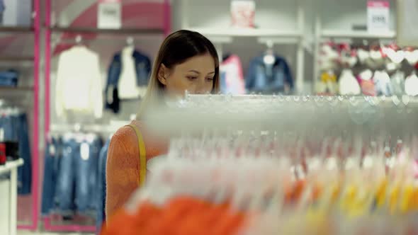 Pretty Long Haired Girl in Orange Blouse Chooses