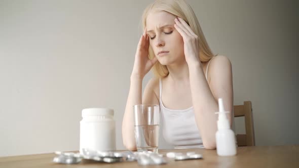 Sick Sad Young Woman Sits at the Table with Different Medications