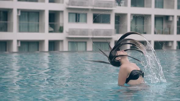 Lady in Bikini Splashes Water with Hair in Pool Slow Motion