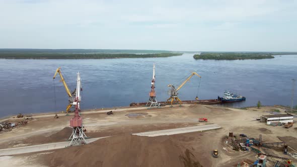 Large Harbor Cranes Onshore at the Quay Unload a River Gravel Barge Onto a Large Pile