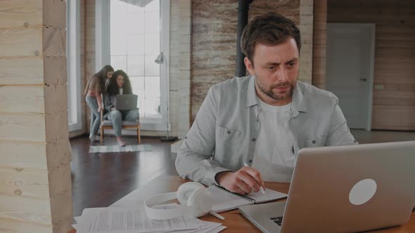 Man Working at the Laptop at Home Because of Covid19 Family in the Background