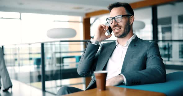 Pensive Young Businessman in Cafe Using Phone