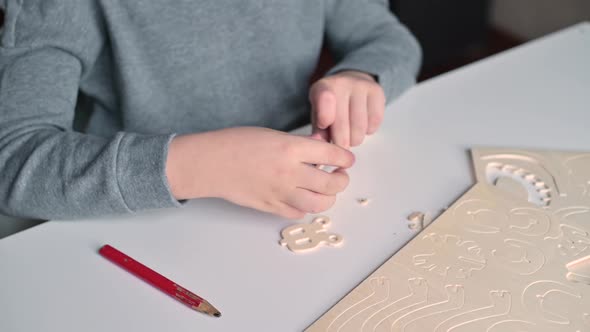 hands of a boy who assembles a wooden constructor