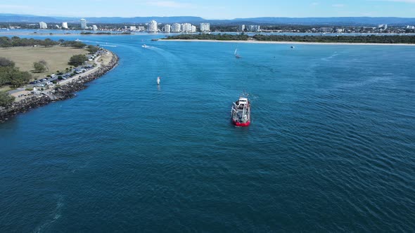 Large sand dredging ship positioned in the middle of a popular city harbor for coastal replenishment