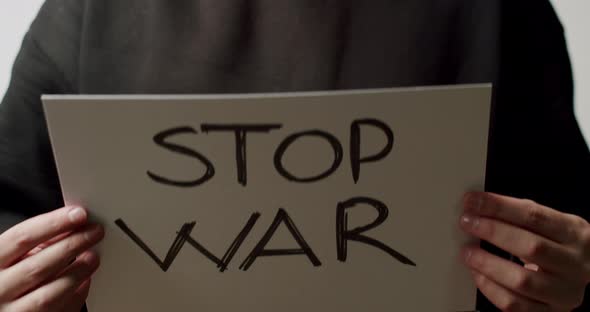 Person Holding a White Paper with a Message No War