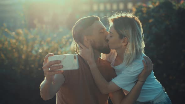 Kissing young couple makes selfie