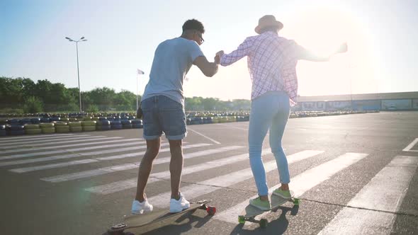 Young Attractive Mixed Race Couple Riding Skateboards and Having Fun Slow Motion