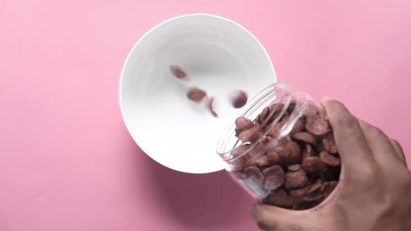 Chocolate Corn Flakes Pouring in a Bowl on Pink