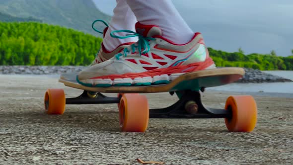 A Teenager Rides a Longboard Along a Beautiful Road with Green Palm Trees
