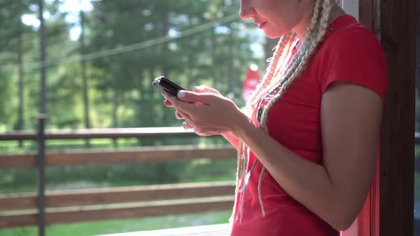 Happy Woman Uses Mobile Internet on Her Smartphone in a Country House