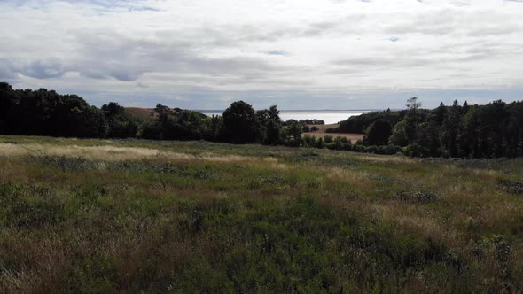 Aerial view of the coastline of Sejerøbugten with hills, fields and ocean.